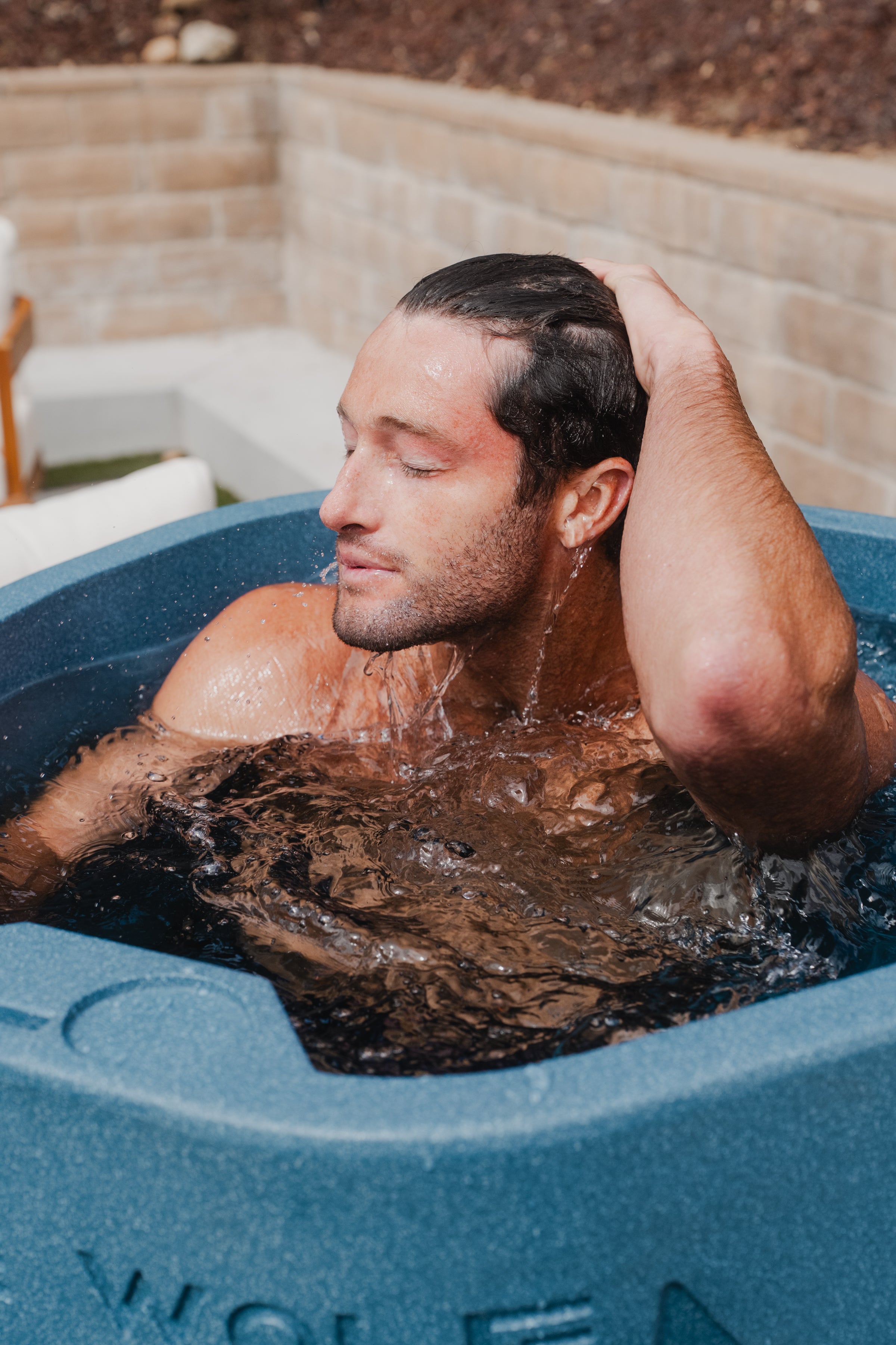 Man emerging from blue cold plunge tub 
